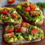 Avocadobrot mit Tomaten und Basilikum 3 Avocadobrot mit frischen Tomaten und Basilikum auf einem Holzbrett präsentiert.