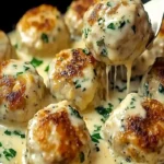Hähnchen-Ricotta-Frikadellen mit cremiger Spinat-Alfredo-Sauce 4 Hähnchen-Ricotta-Frikadellen mit Spinat-Alfredo-Sauce auf einem Teller