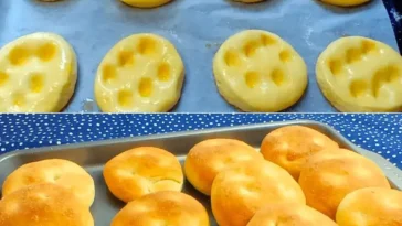 Frisch gebackene Käse-Minibrötchen auf einem Holzbrett.