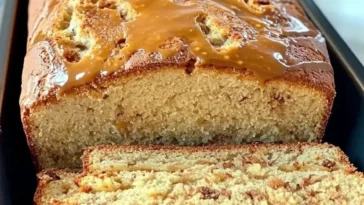 Ein saftiger Nusskuchen auf einem Teller, garniert mit Nüssen und Puderzucker.