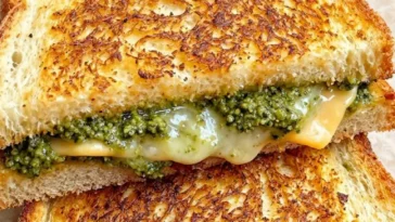 Leckeres Pesto-Toastie mit frischem Basilikum und Käse auf knusprigem Brot.