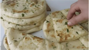 Räucherkäse gefüllte Knoblauchfladen auf einem Holzbrett