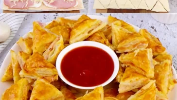 Blätterteig-Dreiecke gefüllt mit Käse und Schinken auf einem Teller