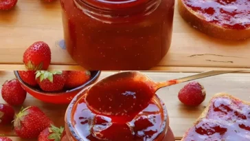 Hausgemachte Erdbeermarmelade in einem Glas mit frischen Erdbeeren